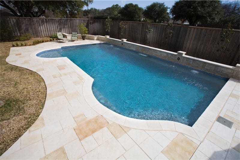 Custom pool with concrete patio deck and water feature