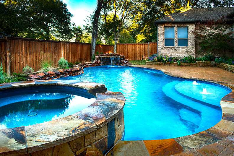 A concrete pool surrounded by landscaping