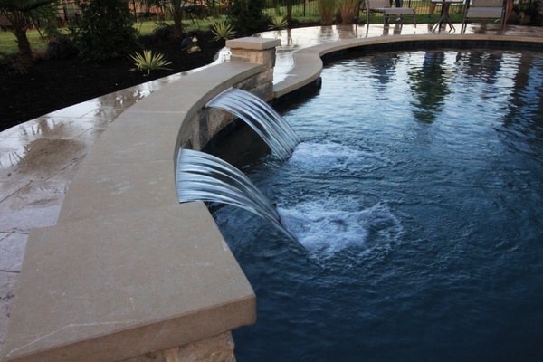 New water feature installed in a pool surrounded by a deck and landscaping