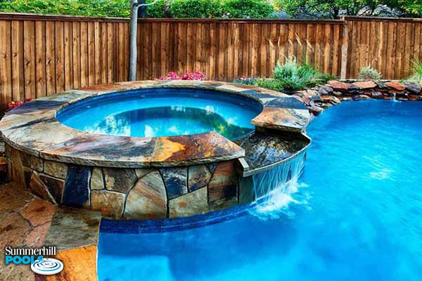stone spa with water wall into a pool
