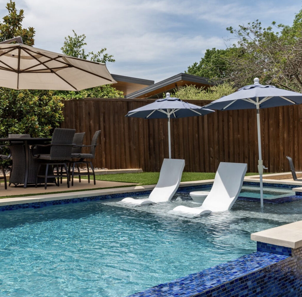 Stylish poolside setup with shaded in-water loungers and outdoor dining area—perfect for relaxing and entertaining in a private backyard.