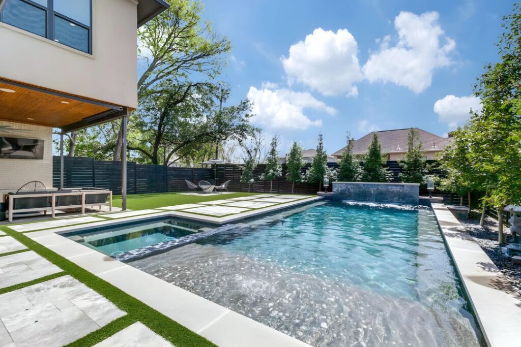 Summerhill Pools installation featuring spa integration, stone waterfall, and modern patio layout for high-end residential backyard design.