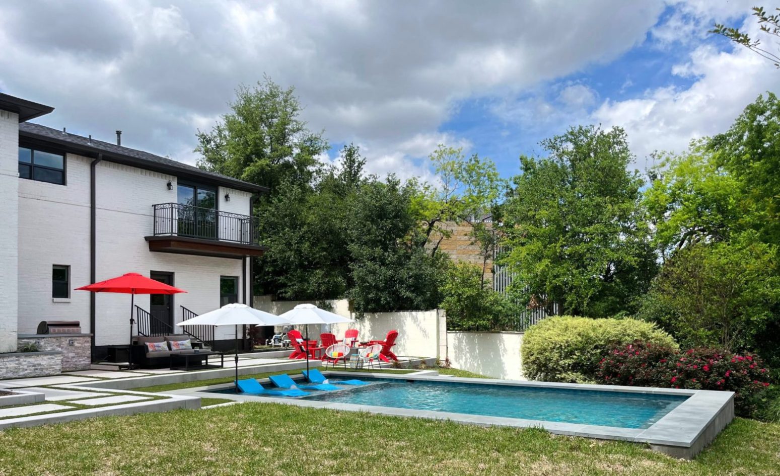 Stylish outdoor living space with rectangular pool, shaded lounge area, and lush landscaping—perfect for family relaxation and entertaining.