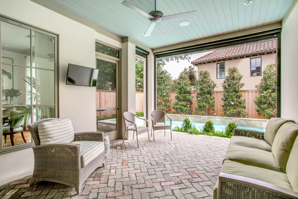 Luxury backyard design showcasing a rectangular pool, integrated sun shelf, and a stone-clad outdoor kitchen pavilion alongside a contemporary paver and turf lawn.