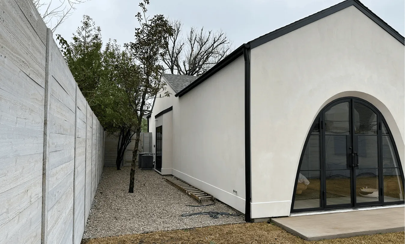 Modern arched glass doors and clean white stucco exterior of a residential home, showcasing the sleek design and site potential for a new pool build.