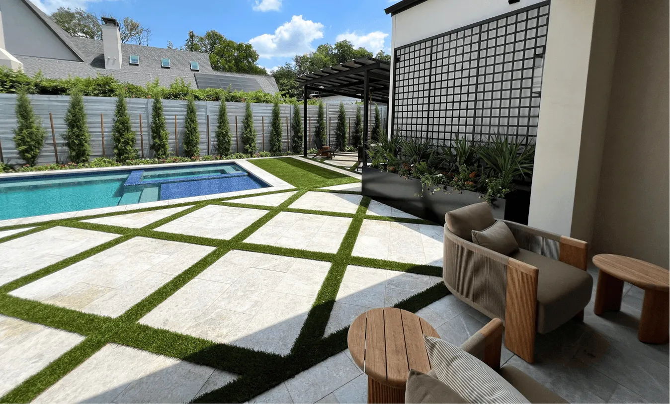Full view of a modern backyard oasis with a blue-tiled pool, luxury patio furniture, and architectural landscaping under a bright sky.