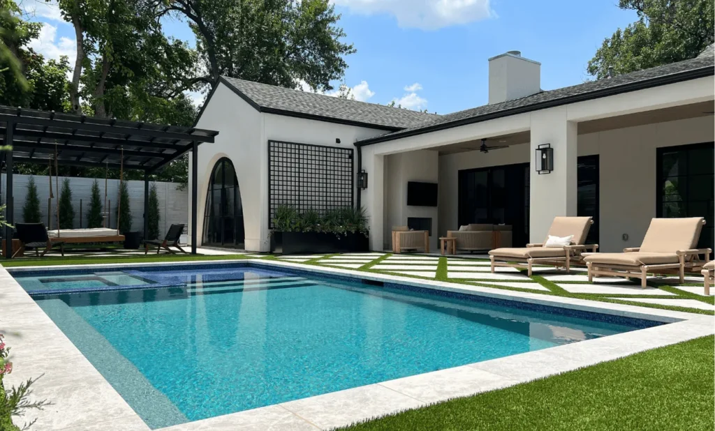 Comprehensive backyard transformation featuring a geometric inground pool, sun shelf, integrated spa, and an outdoor living room with a covered patio and custom steel planters.