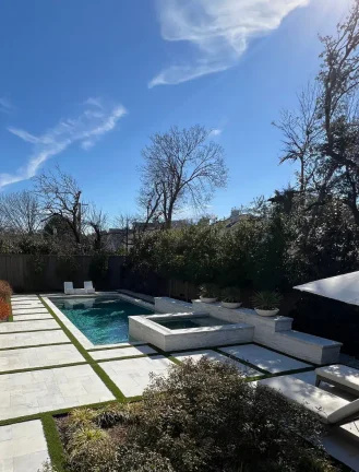 Modern geometric pool with custom white stone feature wall, integrated spa, and premium Ledge Lounger furniture.